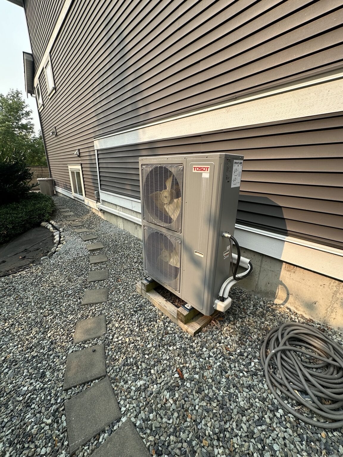 TOSOT cold-climate central heat pump installed beside a home.